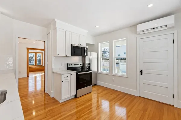 a view of a kitchen with wooden floor electronic appliances and window