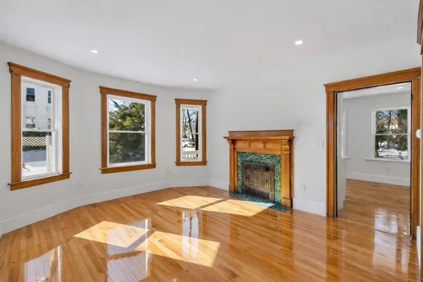 a view of an empty room with window and wooden floor