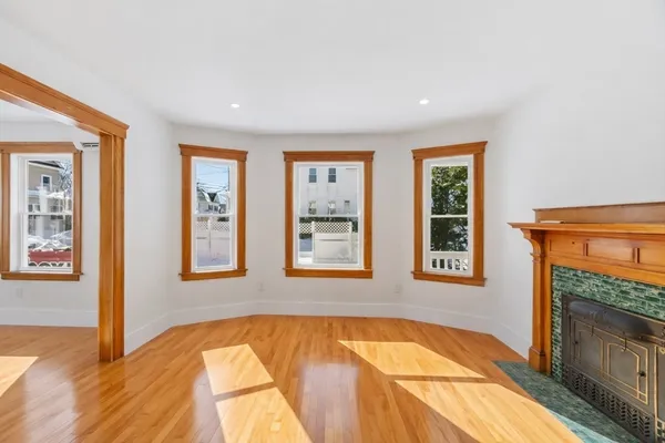 a view of an empty room with window and wooden floor