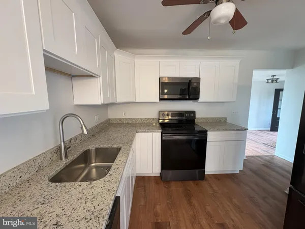 a kitchen with granite countertop a refrigerator and a stove top oven