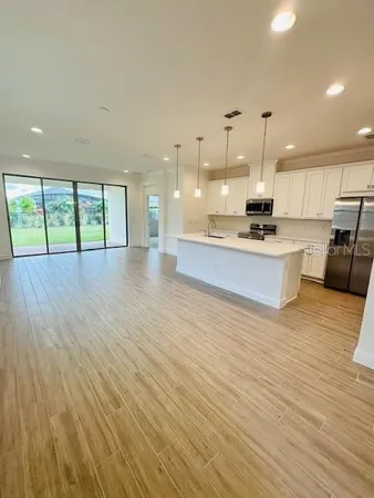 a large kitchen with stainless steel appliances a large counter top a wooden floor a fireplace and a large window