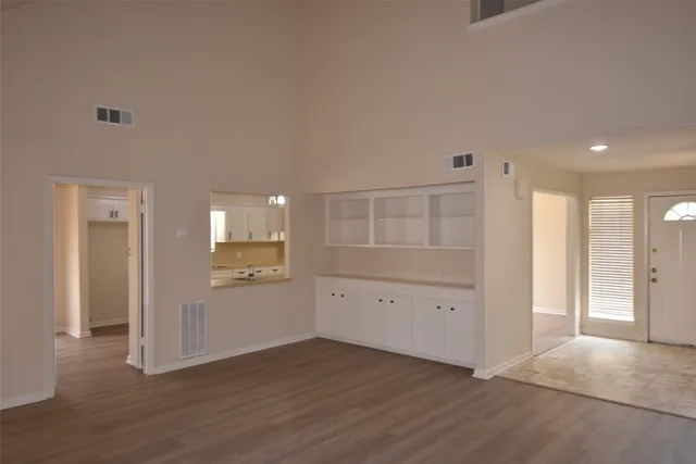 an empty room with wooden floor & cabinet and windows