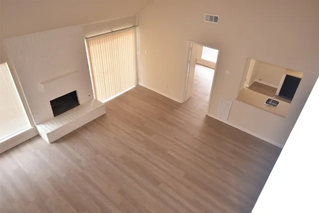 wooden floor in an empty room with a fireplace and a window