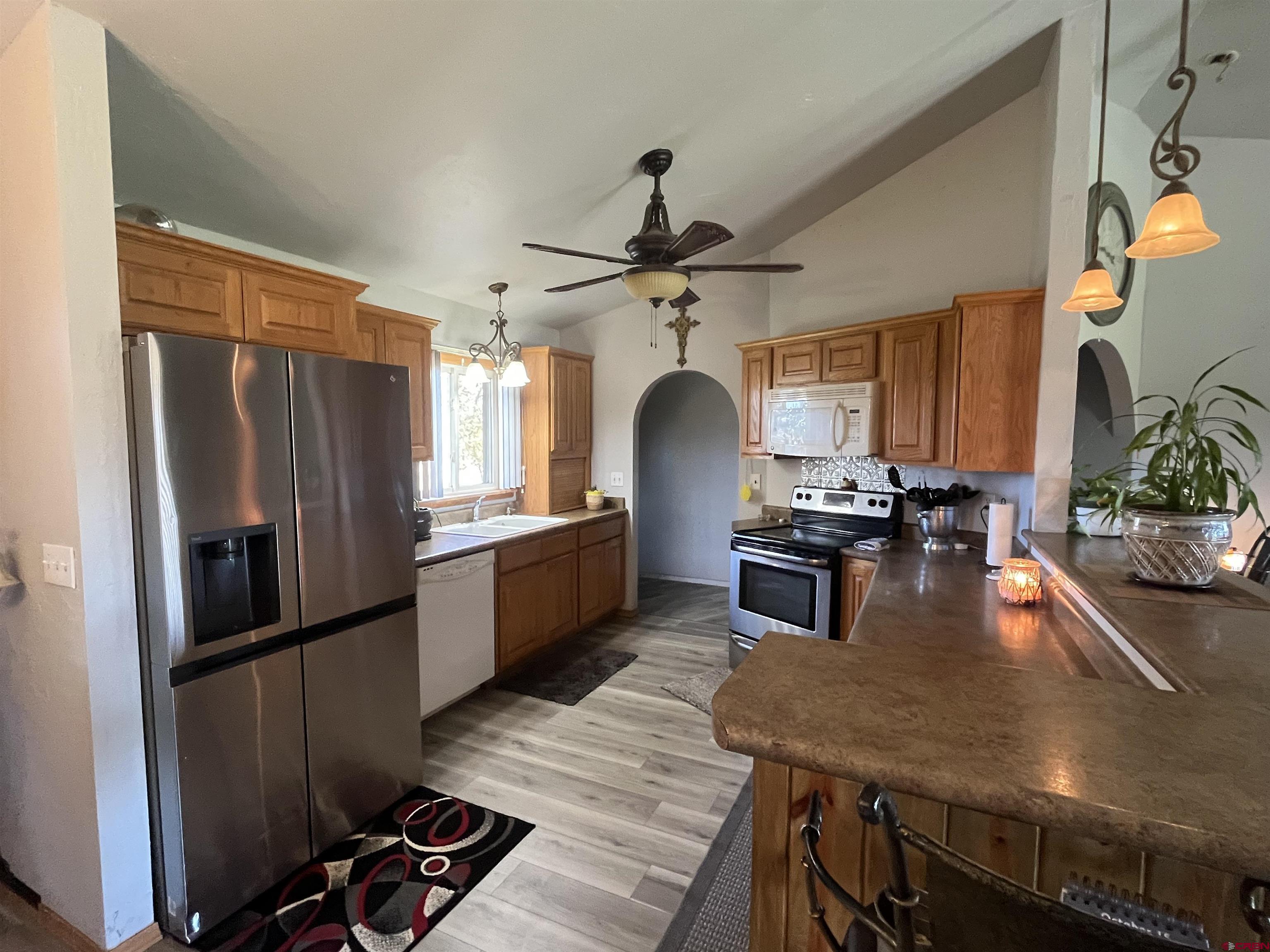 16400 6630 Road Montrose, CO 81401 - Photo 11 of 27 a kitchen with stainless steel appliances granite countertop a refrigerator a sink dishwasher a stove and white countertops with wooden floor