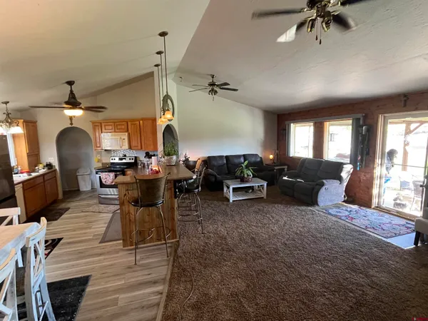 a kitchen with stainless steel appliances granite countertop a refrigerator a sink dishwasher a stove and white countertops with wooden floor