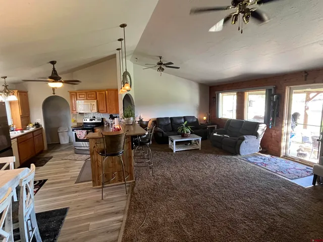 a kitchen with stainless steel appliances granite countertop a refrigerator a sink dishwasher a stove and white countertops with wooden floor