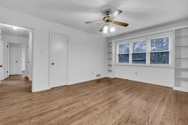 a view of empty room with wooden floor and fan