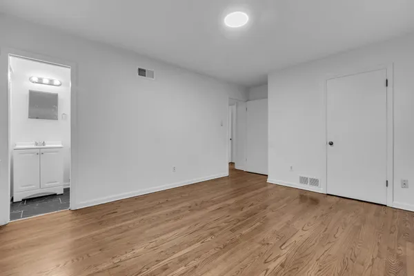 a view of an empty room with wooden floor and a sink