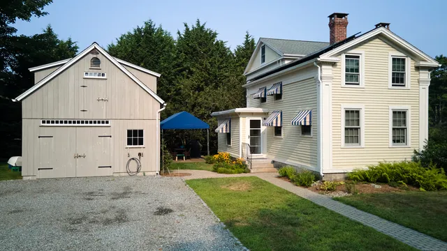 a view of a white house with yard and trees in front of it
