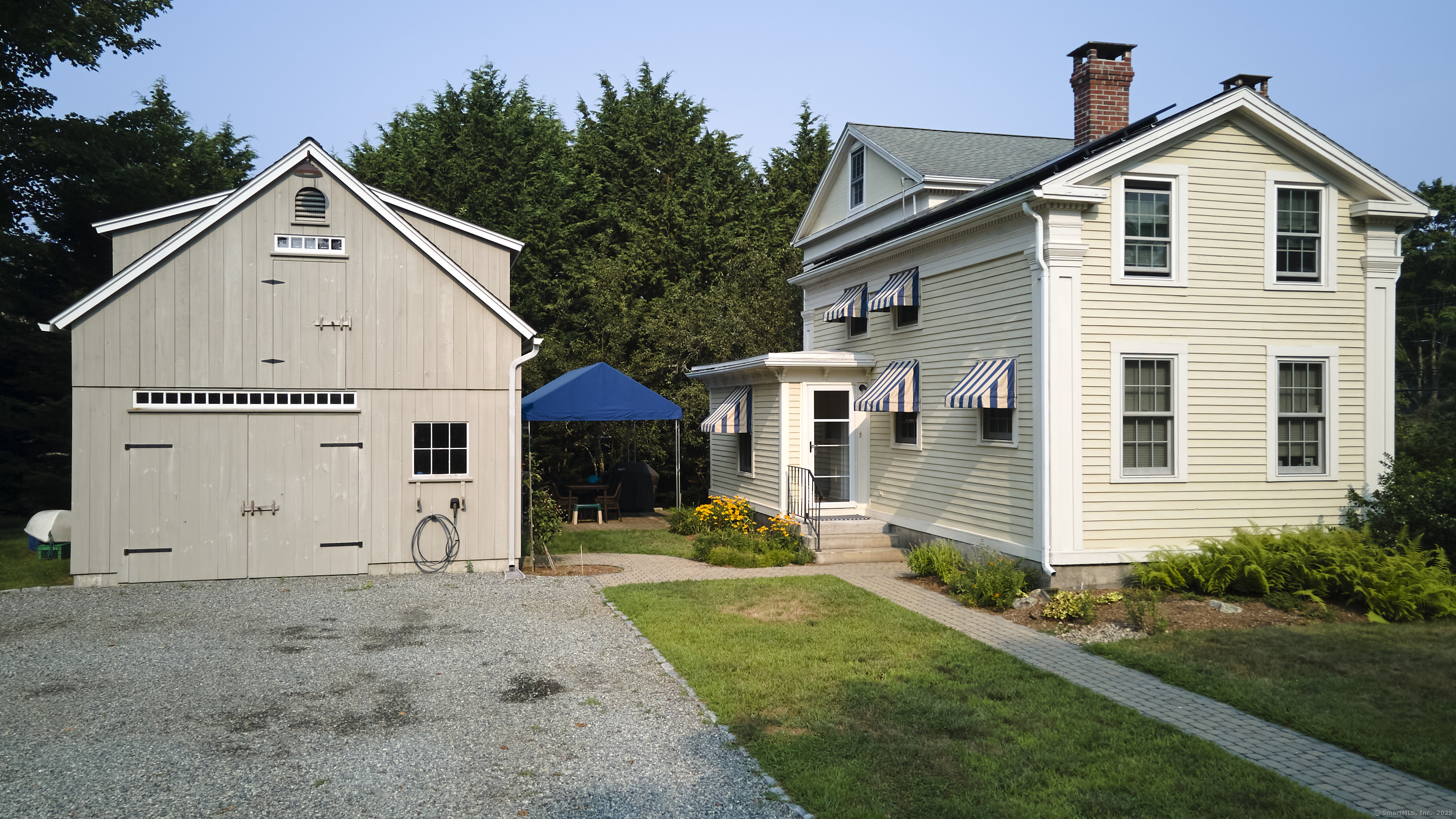 a view of a white house with yard and trees in front of it