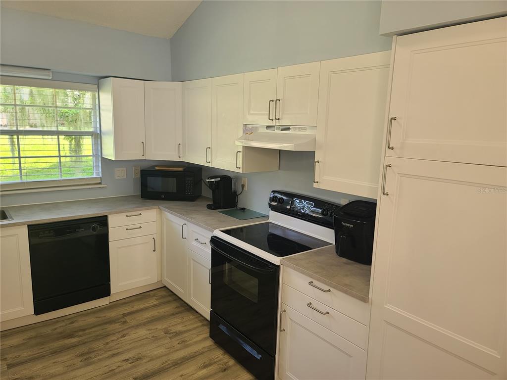 11001 Southeast Sunset Harbor Road, Unit C27 Summerfield, FL 34491 - Photo 16 of 53 a kitchen with cabinets appliances and wooden floor