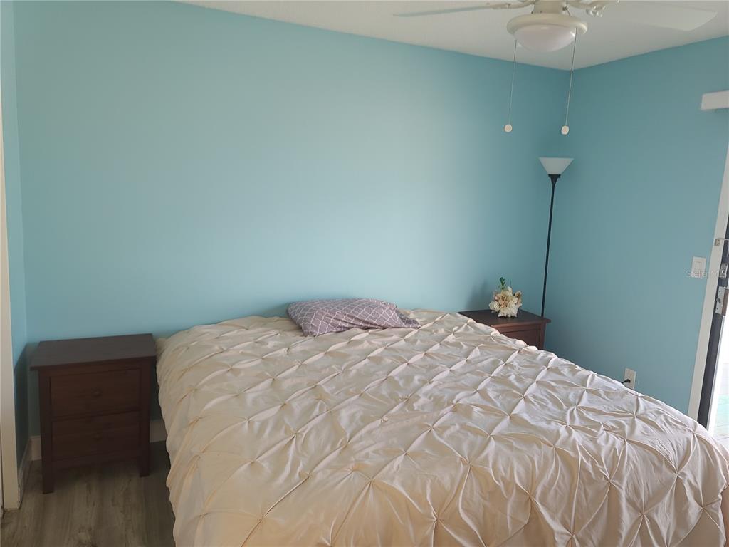 11001 Southeast Sunset Harbor Road, Unit C27 Summerfield, FL 34491 - Photo 23 of 53 a bedroom with a bed and a chandelier fan