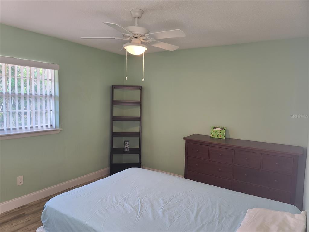 11001 Southeast Sunset Harbor Road, Unit C27 Summerfield, FL 34491 - Photo 34 of 53 a bedroom with a bed and a chandelier