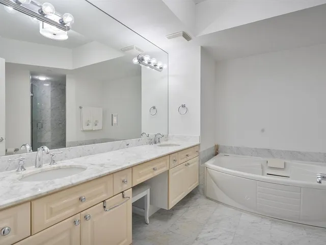 a bathroom with a granite countertop double vanity sink a mirror and a bathtub