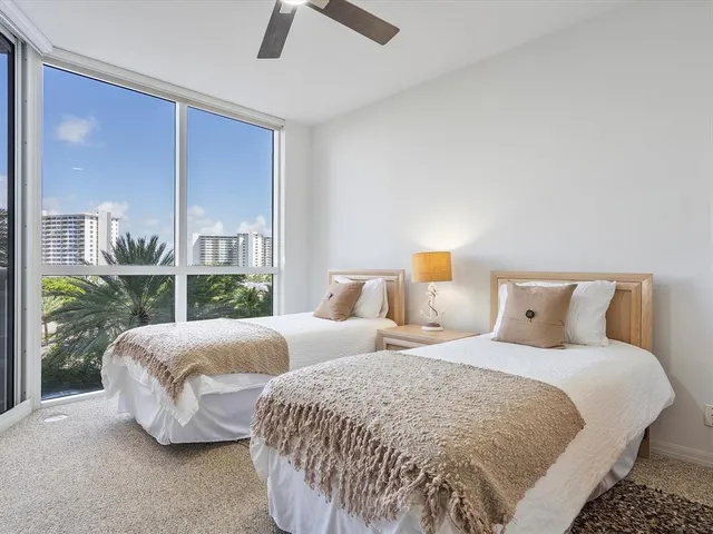 a bedroom with two beds and large window