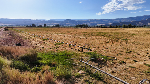 2070 East Tbd Road North Richfield, UT 84701 - Photo 15 of 35 Expansive agricultural land featuring a wheel line irrigation system, a distinct property boundary, and distant mountain backdrops