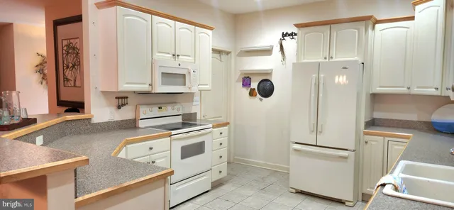a kitchen with a refrigerator a stove and white cabinets with wooden floor