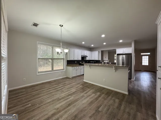 a view of kitchen with kitchen island wooden floor appliances and window