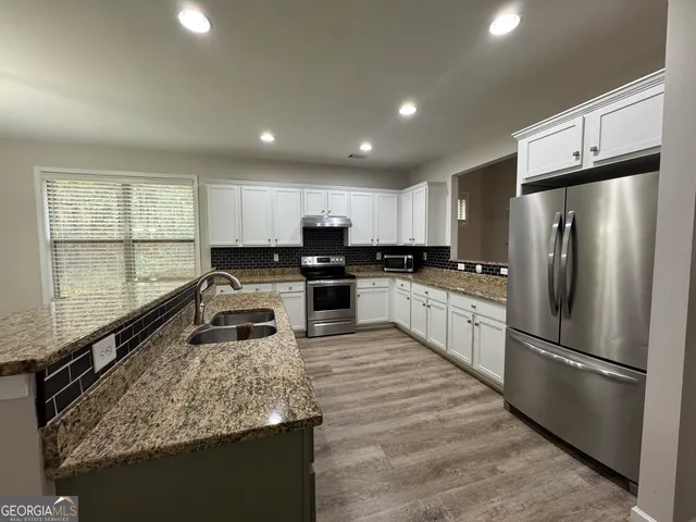 a kitchen with stainless steel appliances granite countertop a refrigerator sink and cabinets