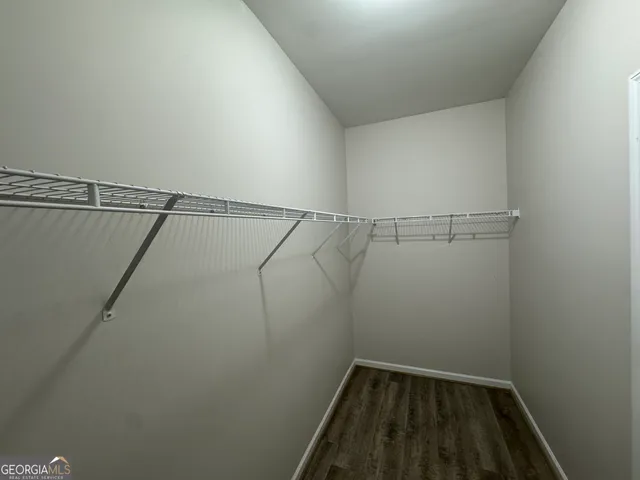 an empty room with wooden floor chandelier fan and windows