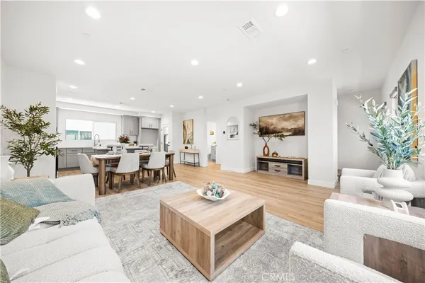 a living room with furniture dining table a rug and kitchen view