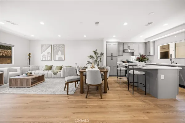 a living room with furniture a wooden floor and kitchen view