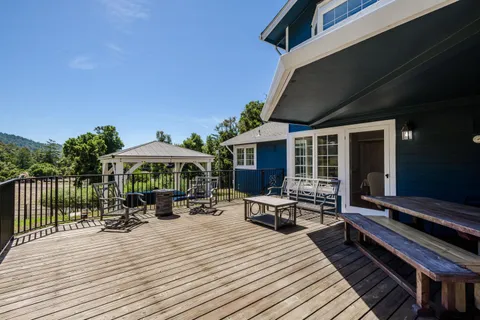 a view of a roof deck with table and chairs under an umbrella with wooden floor
