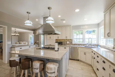 a kitchen with granite countertop stainless steel appliances a sink stove and white cabinets
