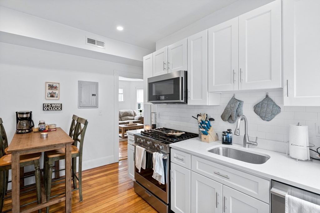 7 Hallam Street, Unit 3 Boston, MA 02125 - Photo 10 of 12 a kitchen with granite countertop a sink a stove a dining table and chairs