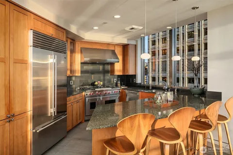 a kitchen with stainless steel appliances granite countertop a refrigerator a stove and a wooden cabinets