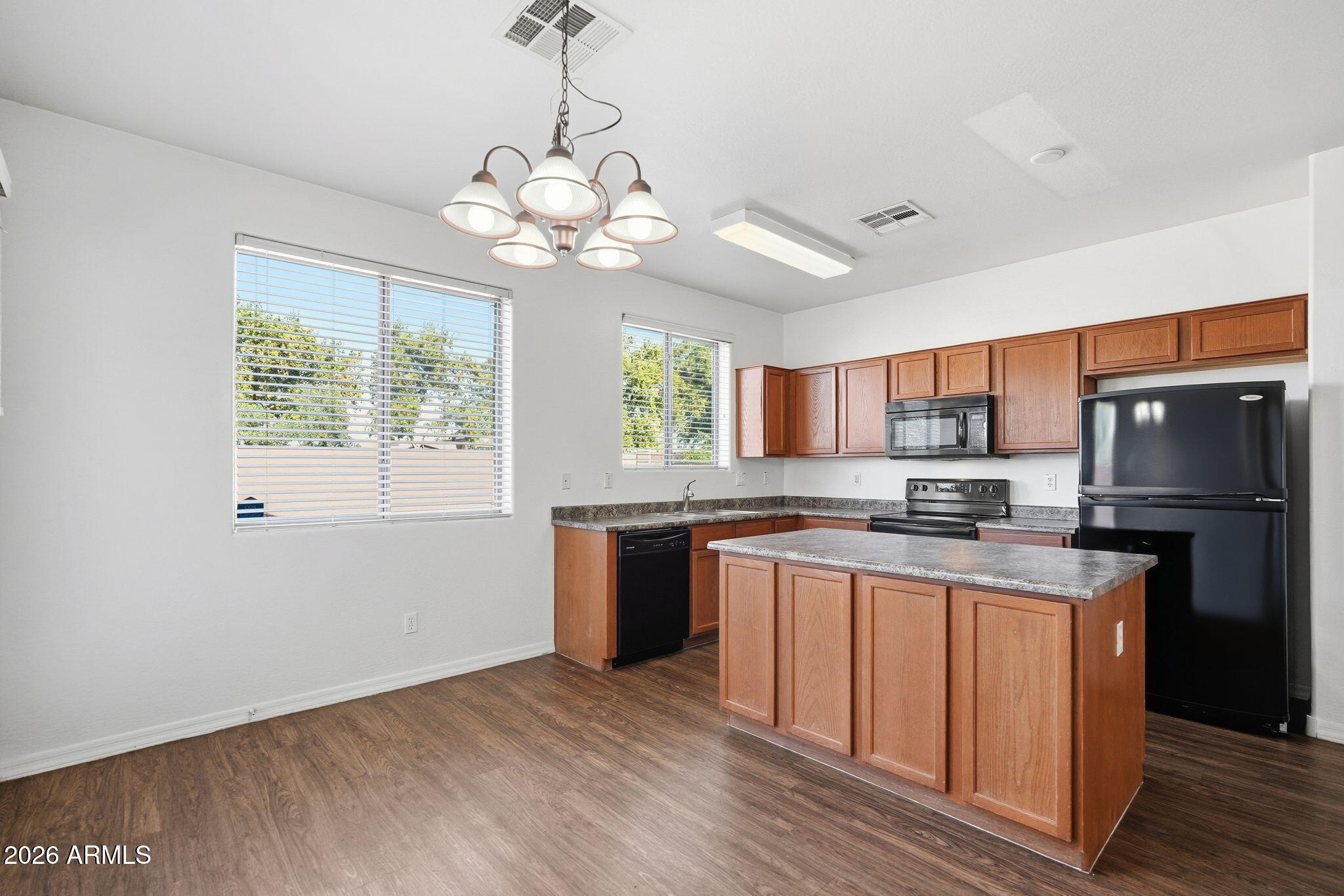 9360 West Payson Road Tolleson, AZ 85353 - Photo 12 of 33 a kitchen with stainless steel appliances granite countertop a stove a sink dishwasher a refrigerator and a dining table with wooden floor