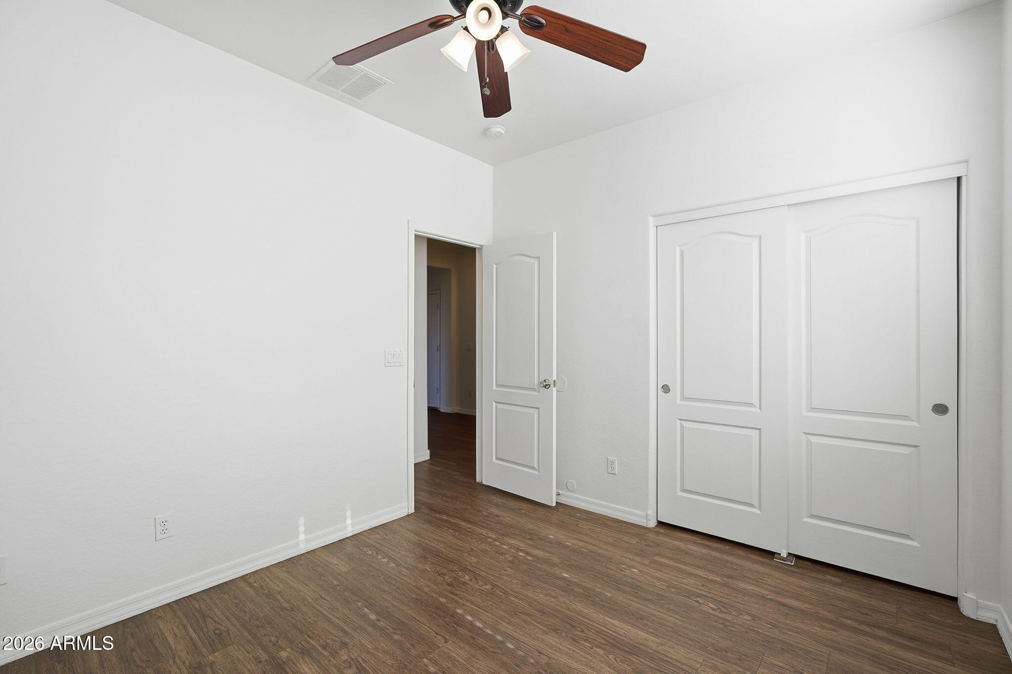 9360 West Payson Road Tolleson, AZ 85353 - Photo 14 of 33 an empty room with wooden floor chandelier fan and windows