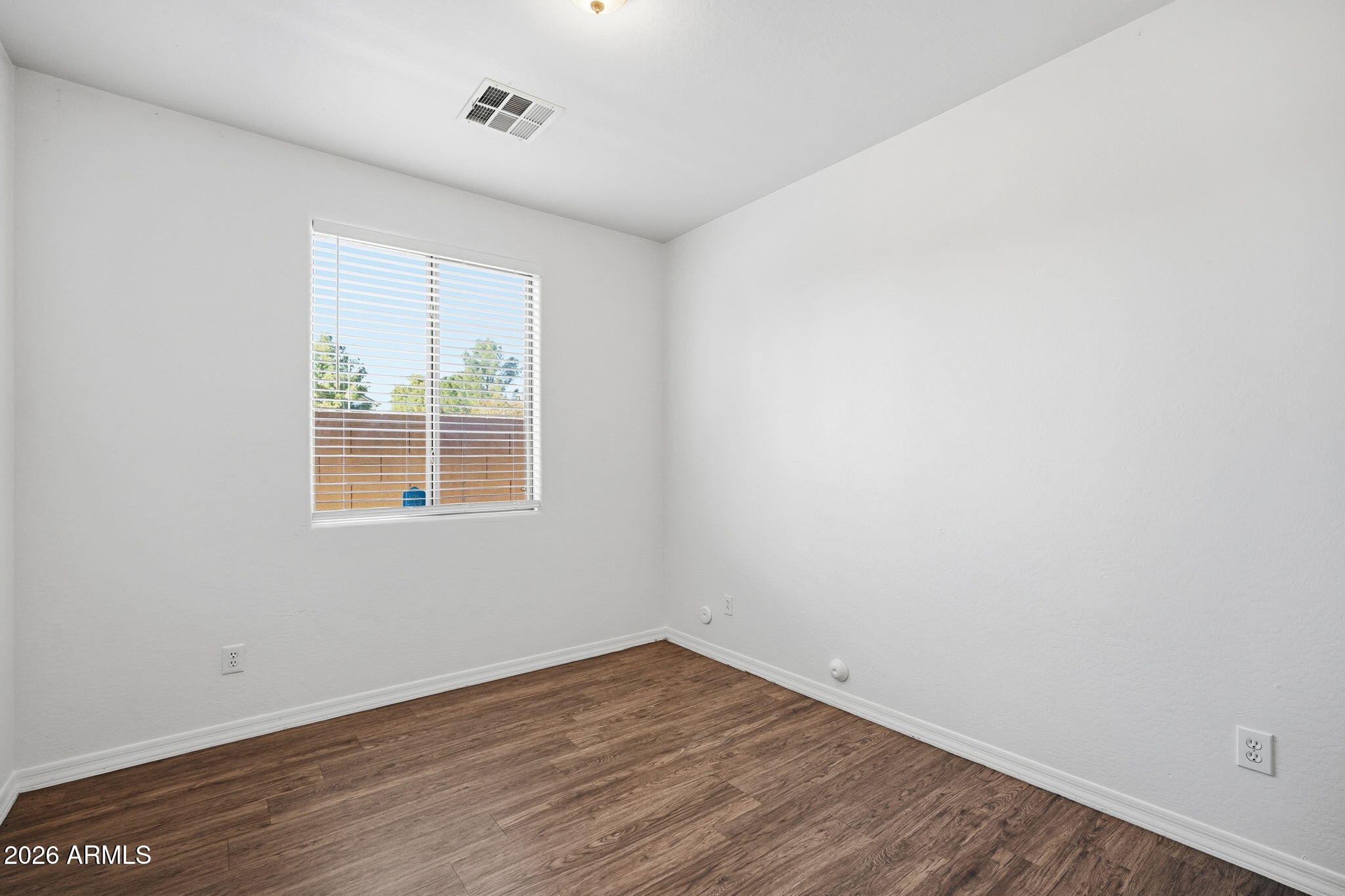 9360 West Payson Road Tolleson, AZ 85353 - Photo 15 of 33 an empty room with wooden floor and windows