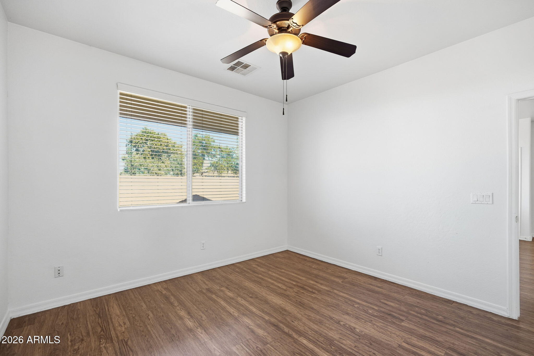 9360 West Payson Road Tolleson, AZ 85353 - Photo 22 of 33 an empty room with wooden floor fan and windows