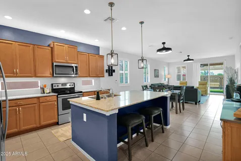 a large kitchen with cabinets chairs sink and stove