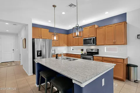 a kitchen with granite countertop a table chairs microwave and refrigerator