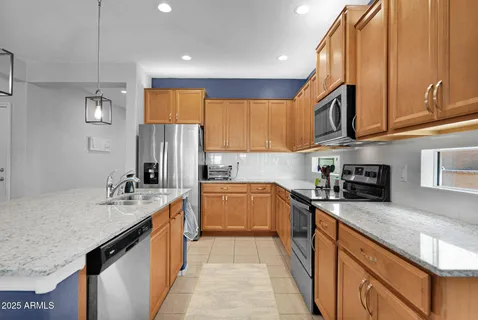 a kitchen with stainless steel appliances granite countertop a sink a stove and a refrigerator