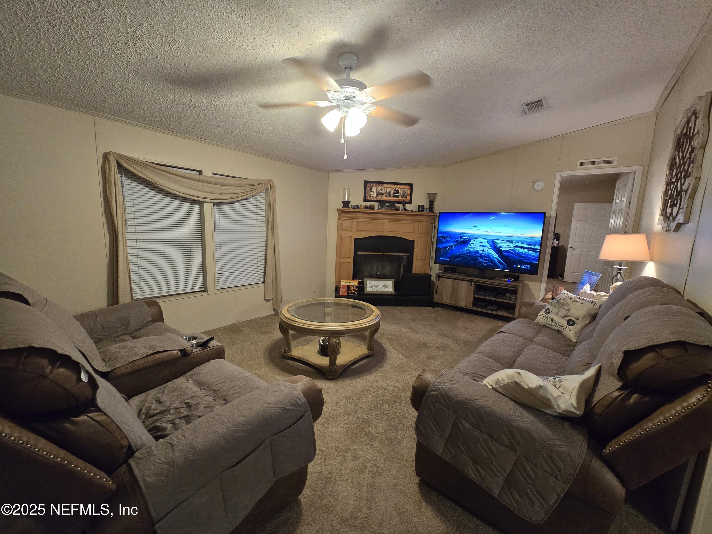85050 Myrtice Road Yulee, FL 32097 - Photo 13 of 87 a living room with furniture a fireplace and a chandelier