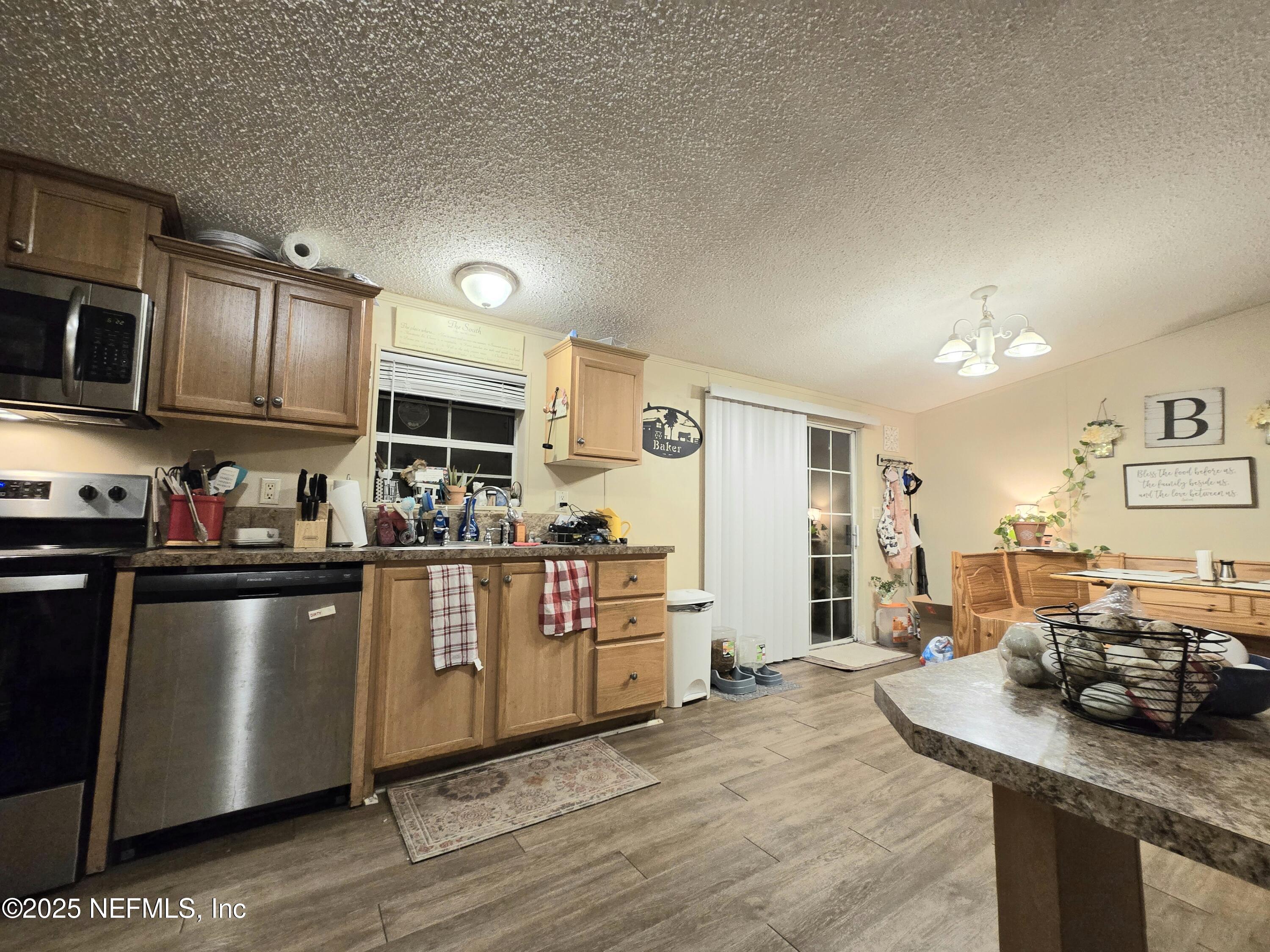 85050 Myrtice Road Yulee, FL 32097 - Photo 17 of 87 a kitchen with stainless steel appliances granite countertop a refrigerator a stove top oven a sink dishwasher and wooden cabinets
