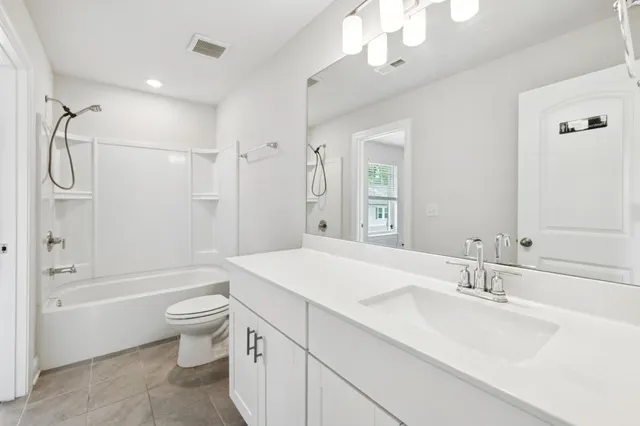 a bathroom with a granite countertop sink a toilet a large mirror and shower