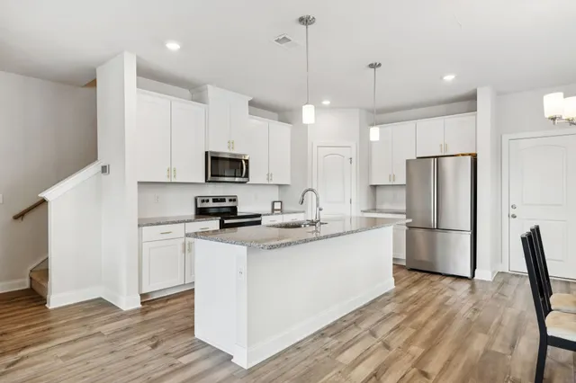 a kitchen with a sink a microwave a refrigerator and white cabinets