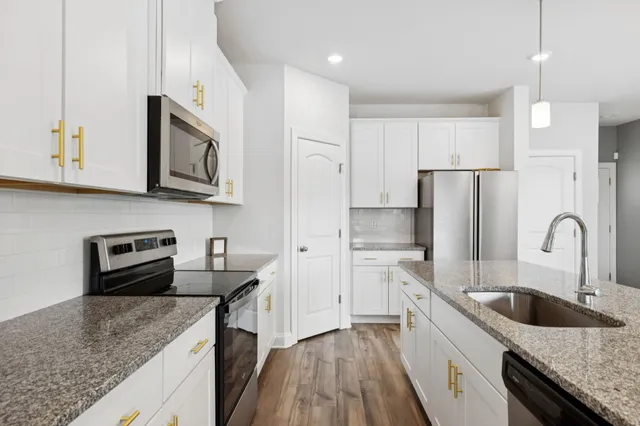 a kitchen with stainless steel appliances granite countertop a sink stove and refrigerator