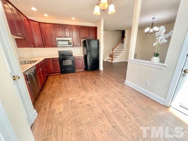 11239 11239th Raleigh, NC 27617 - Photo 11 of 26 a kitchen with stainless steel appliances granite countertop a refrigerator a oven a sink a s island with wooden cabinets and floor