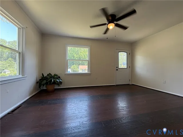 an empty room with wooden floor fan and windows