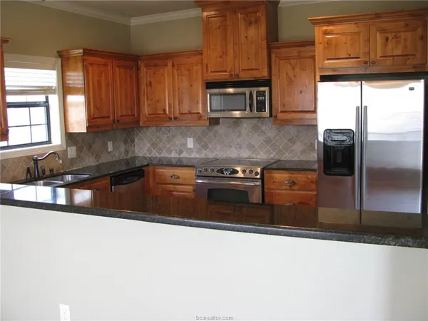 a kitchen with stainless steel appliances granite countertop a stove a sink and a microwave