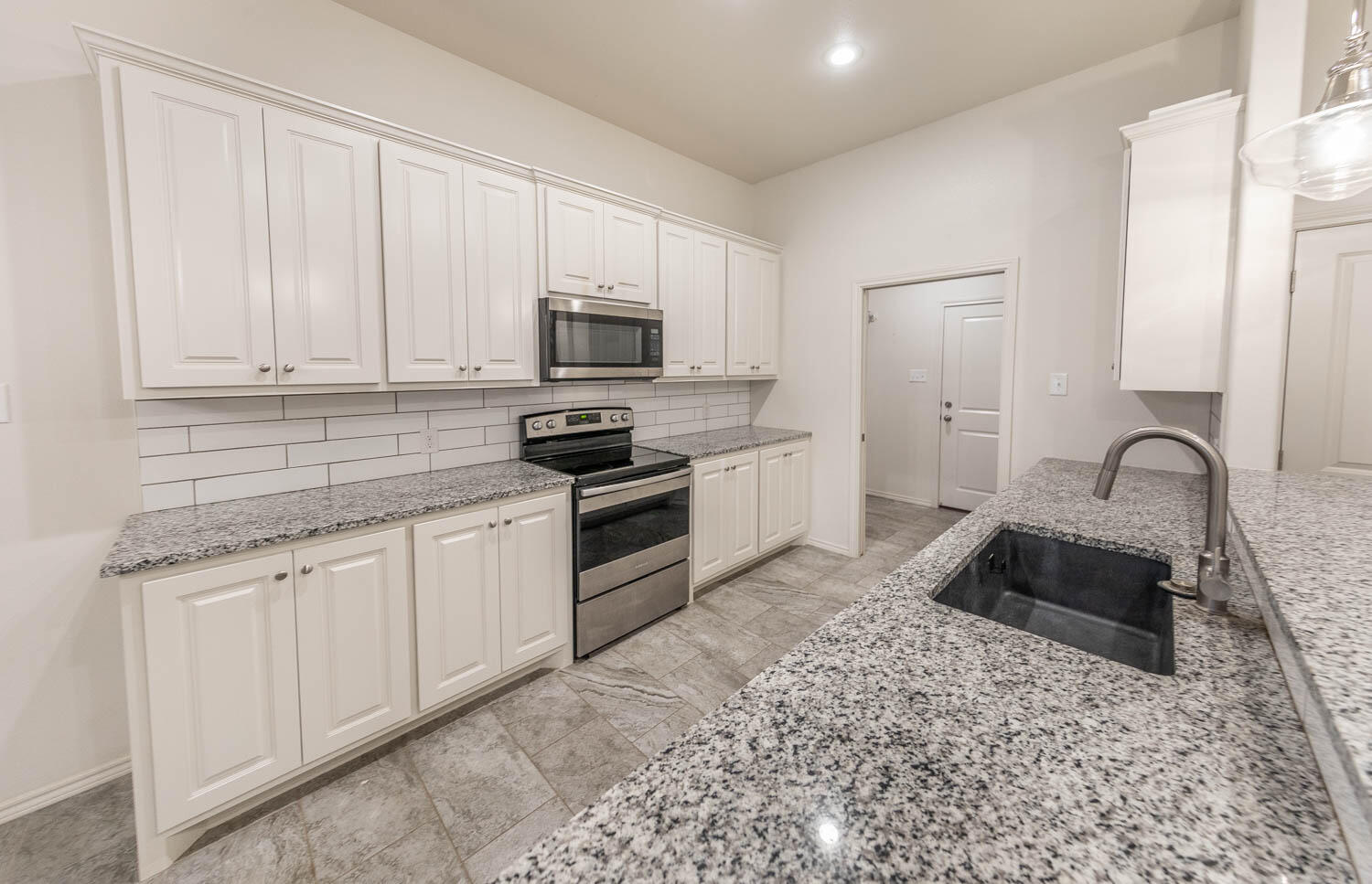 5510 Lehigh Street Lubbock, TX 79416 - Photo 22 of 32 a kitchen with granite countertop white cabinets and stainless steel appliances