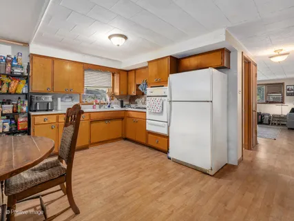 a kitchen with a refrigerator a stove and a dining table with wooden floor