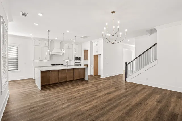 a view of an empty room with wooden floor fireplace and a window