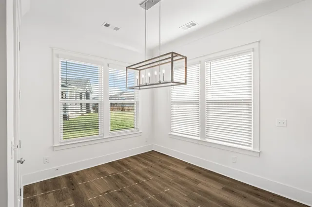 a view of an empty room with wooden floor fireplace and a window