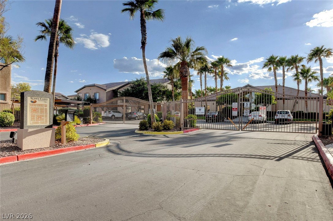 8985 South Durango Drive, Unit 2187 Las Vegas, NV 89113 - Photo 58 of 73 Secure community entrance featuring stately wrought iron gates and flourishing palm trees.